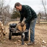 Homme utilisant une fendeuse à bûches thermique dans un jardin rural en automne